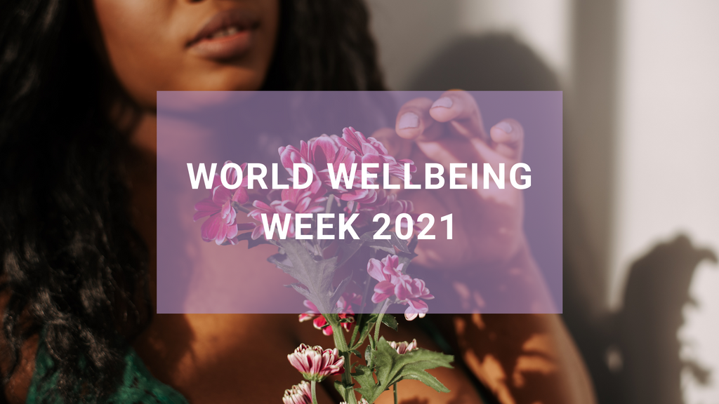 Close-up photograph of a brown-skinned woman holding a bouquet of pink flowers with the text World Wellbeing Week 2021 overlaid.